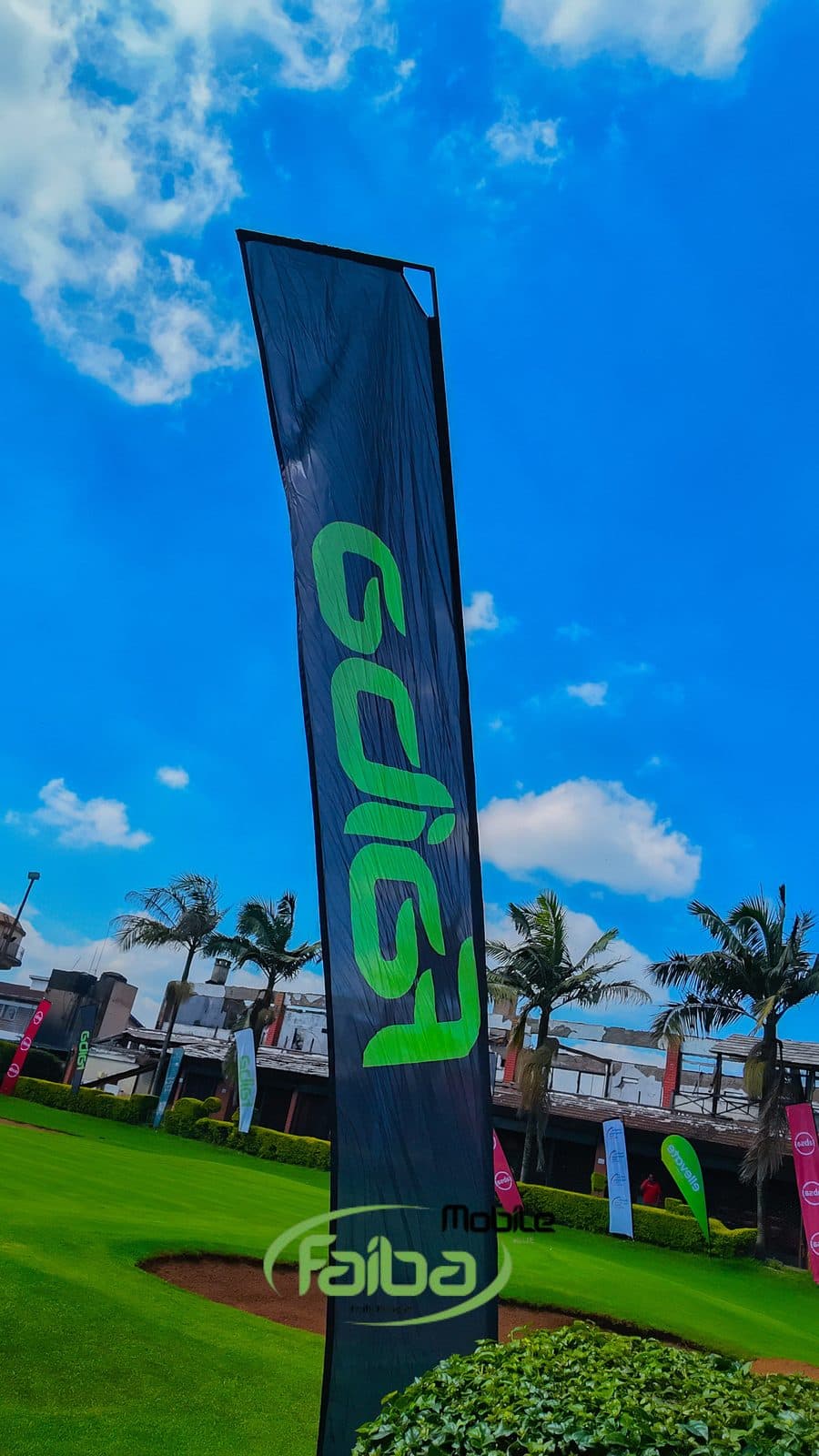 A Faiba Giga banner standing on the fairway at Sigona Golf Club, clubhouse and palms behind it