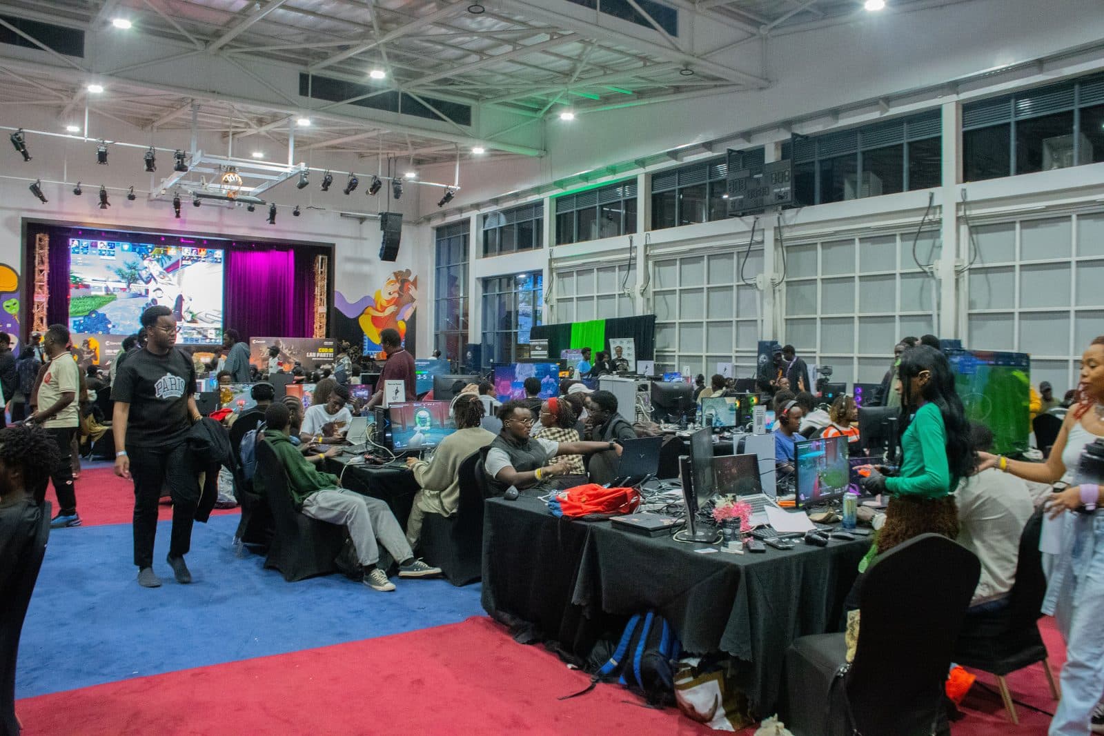 The Lanarchy tournament floor: rows of gaming stations under stage lighting, with live gameplay on a large screen above the crowd